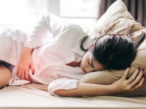 Mulher deitada de lado com dor abdominal